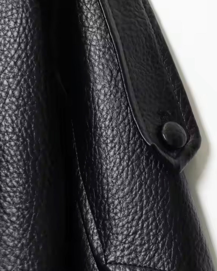 Close-up of a black leather jacket with a button on a white background