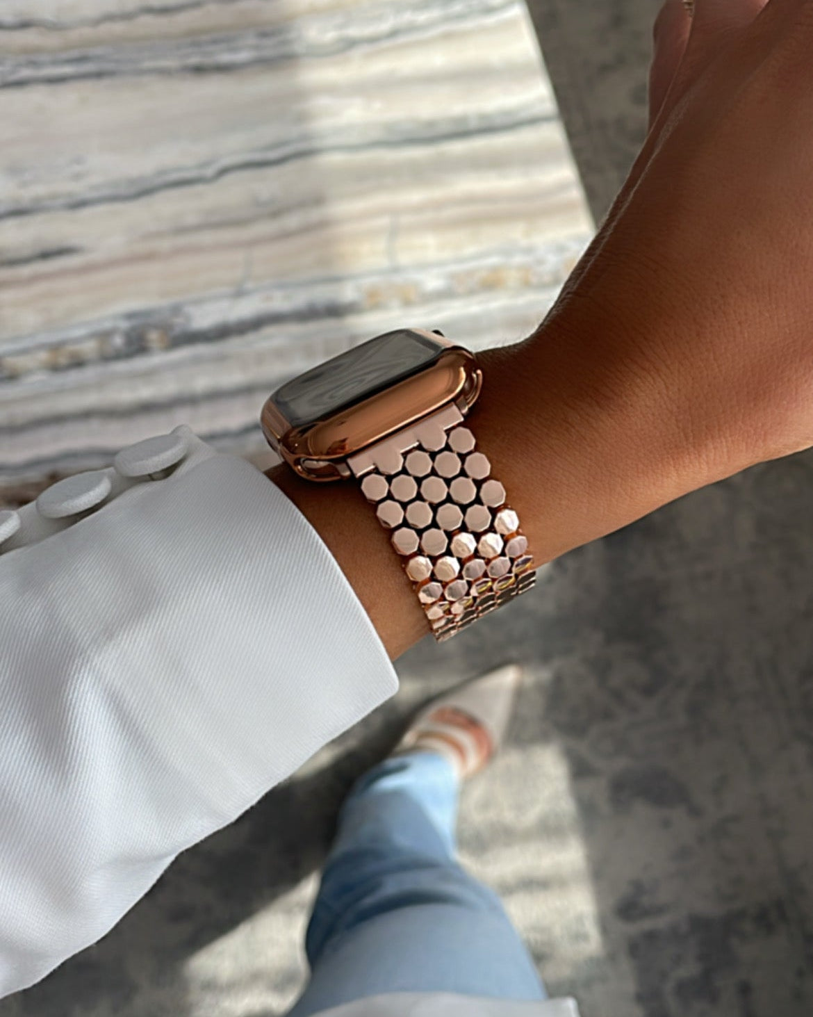 Person wearing a rose gold watch with a textured strap on a neutral background