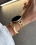 Hand wearing a gold bracelet on a neutral background