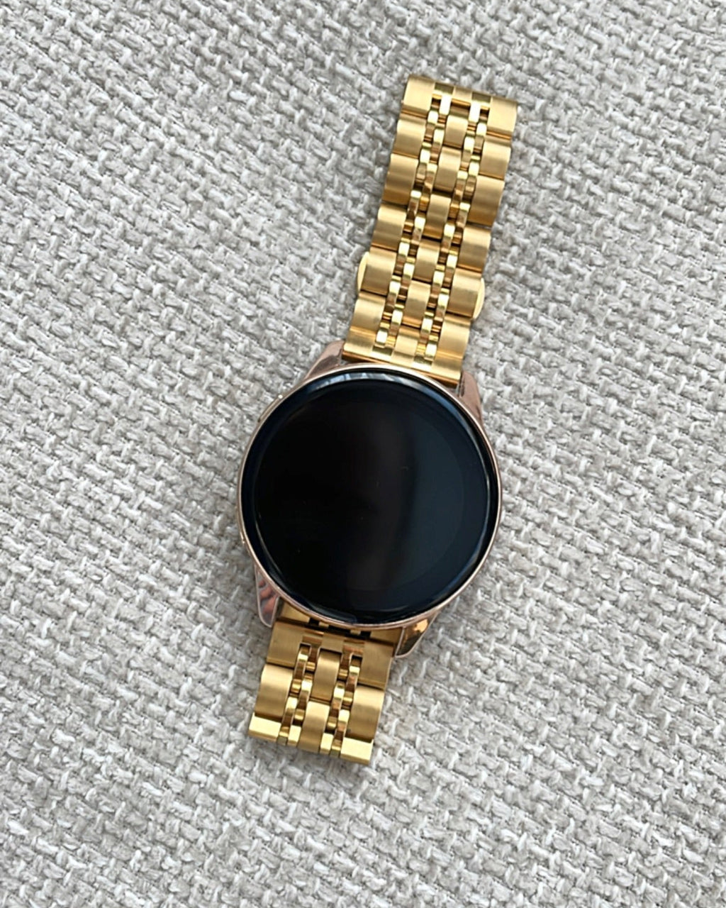 Gold smartwatch on a textured gray surface
