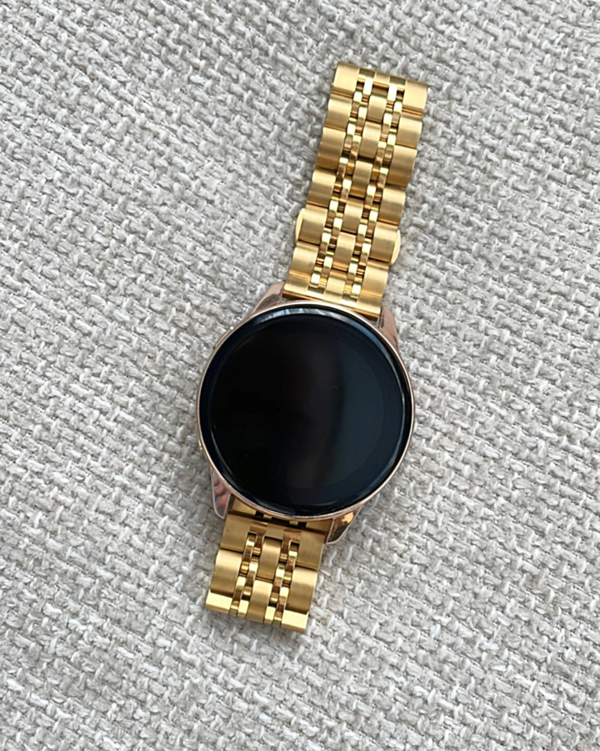 Gold smartwatch on a textured gray surface