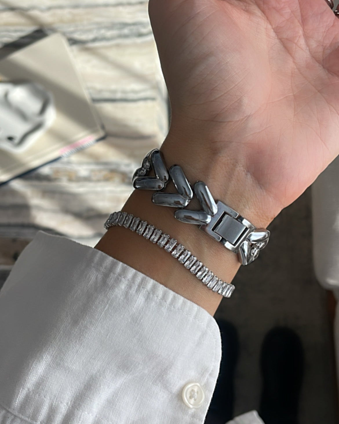 Hand wearing a silver bracelet with a blurred background