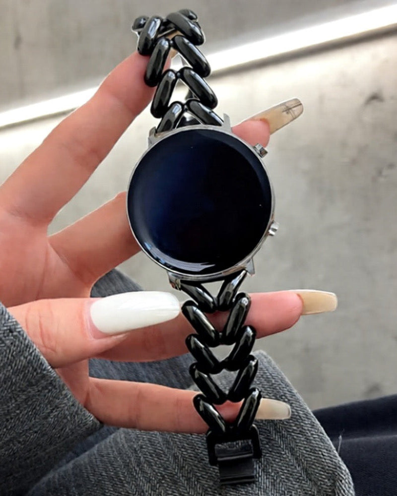 Hand holding a smartwatch with a black chain strap against a neutral background