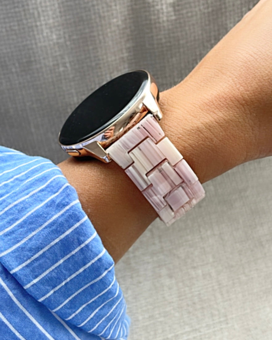 Smartwatch with a pink woven band on a wrist against a gray background