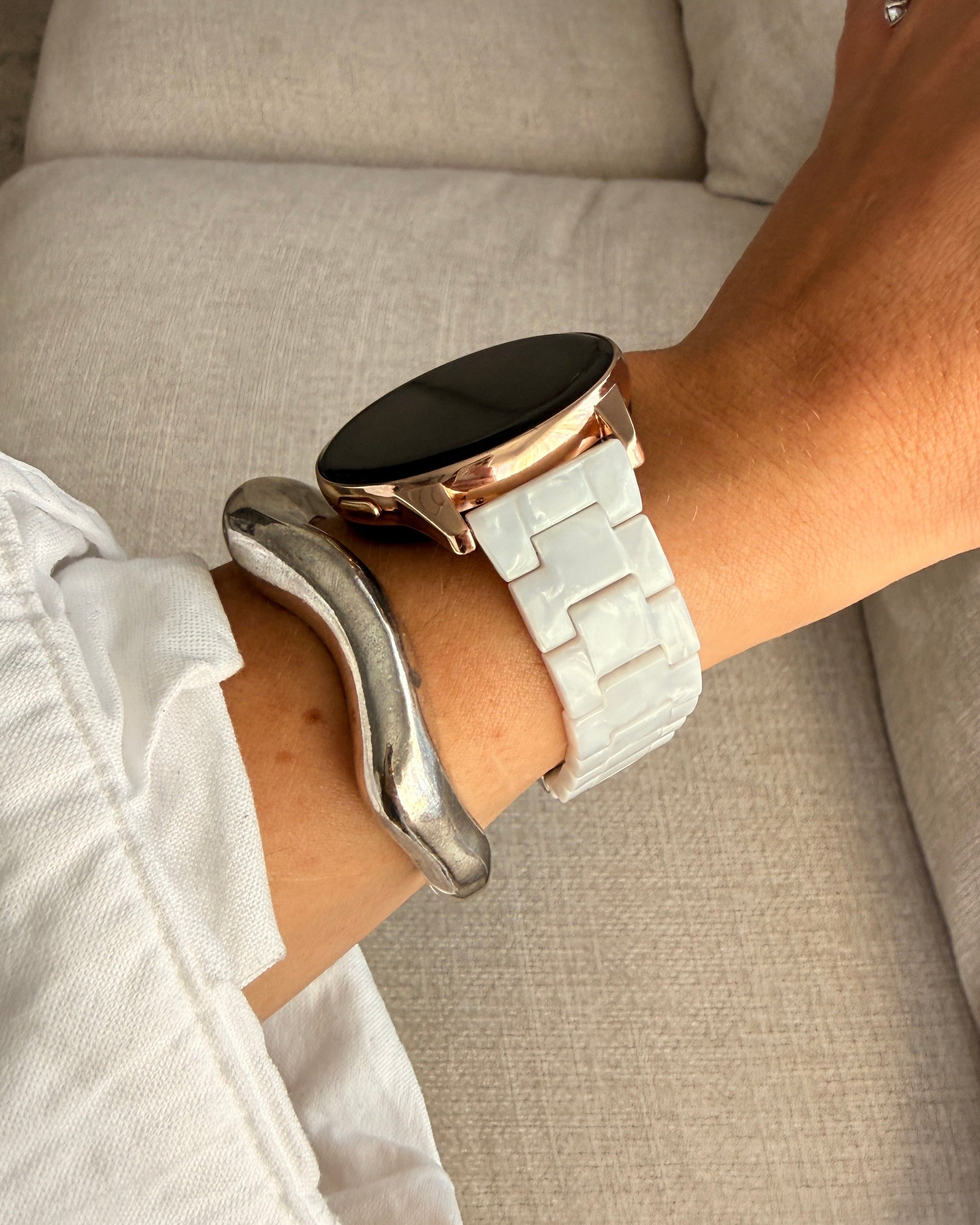 Person wearing a smartwatch with a light-colored strap on a neutral background
