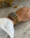 Gold armadillo figurine, gold jubilee date watch apple watch and hand on a gray marble surface