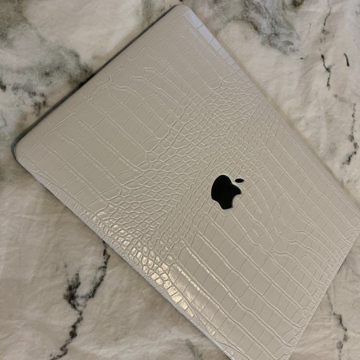 White laptop with textured cover on a marble surface