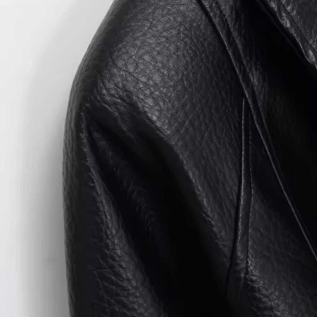 Close-up of a black pebbled leather jacket showing the texture and fold details against a plain white background.