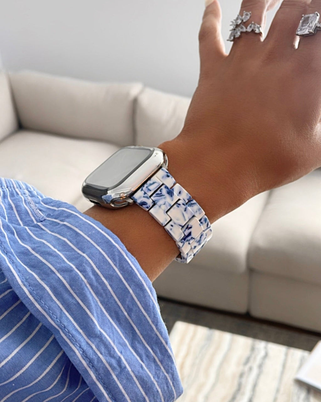 Person wearing a watch with a floral pattern on a neutral background