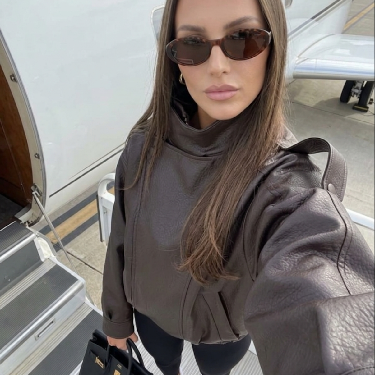 Woman taking a selfie in front of a private jet