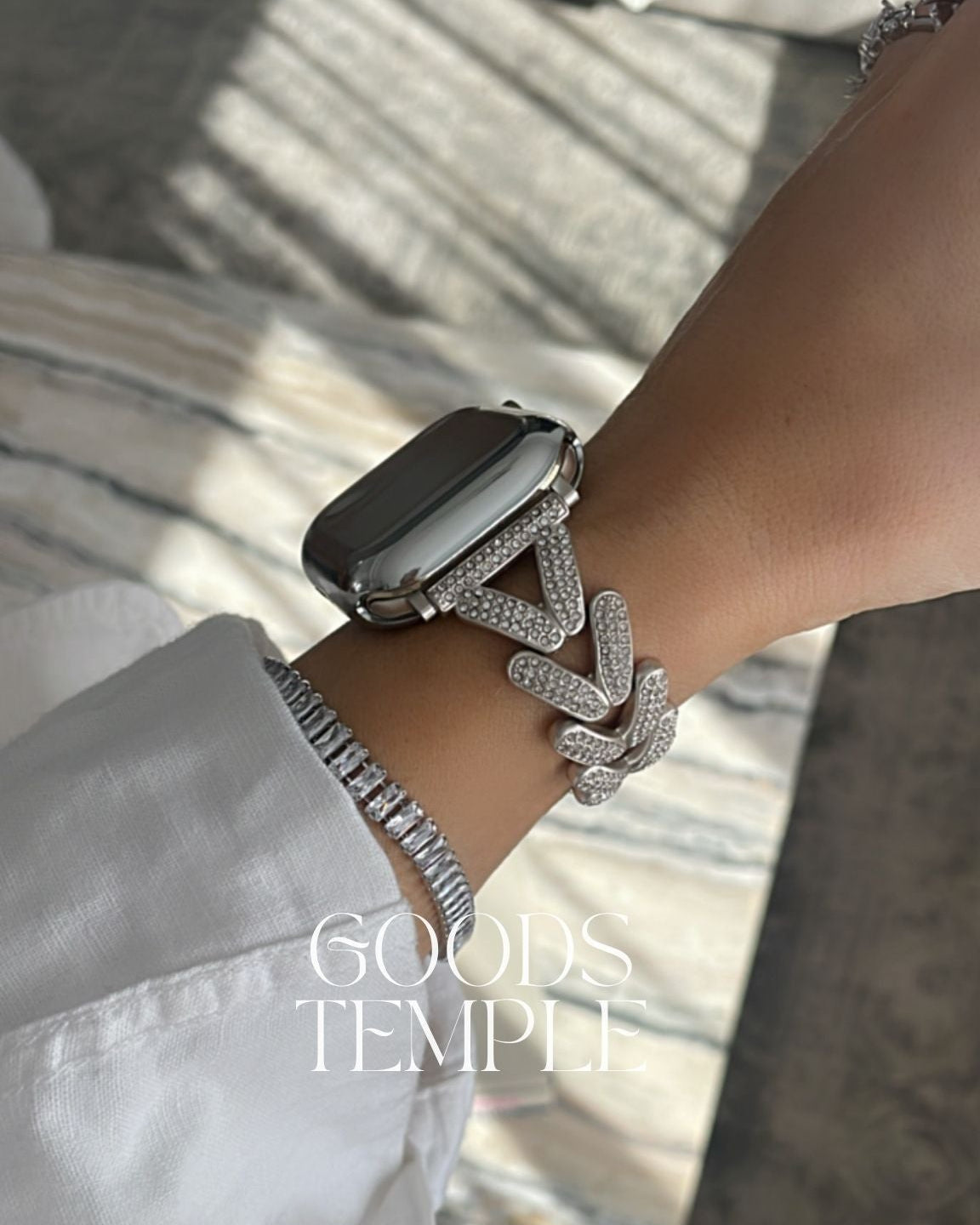 Close-up of a wrist wearing a silver bracelet with 'GOODS TEMPLE' branding.