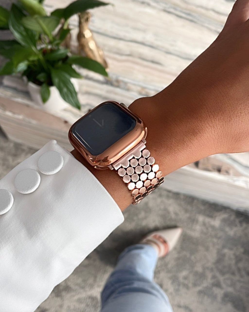 Person wearing a rose gold smartwatch with a blurred background