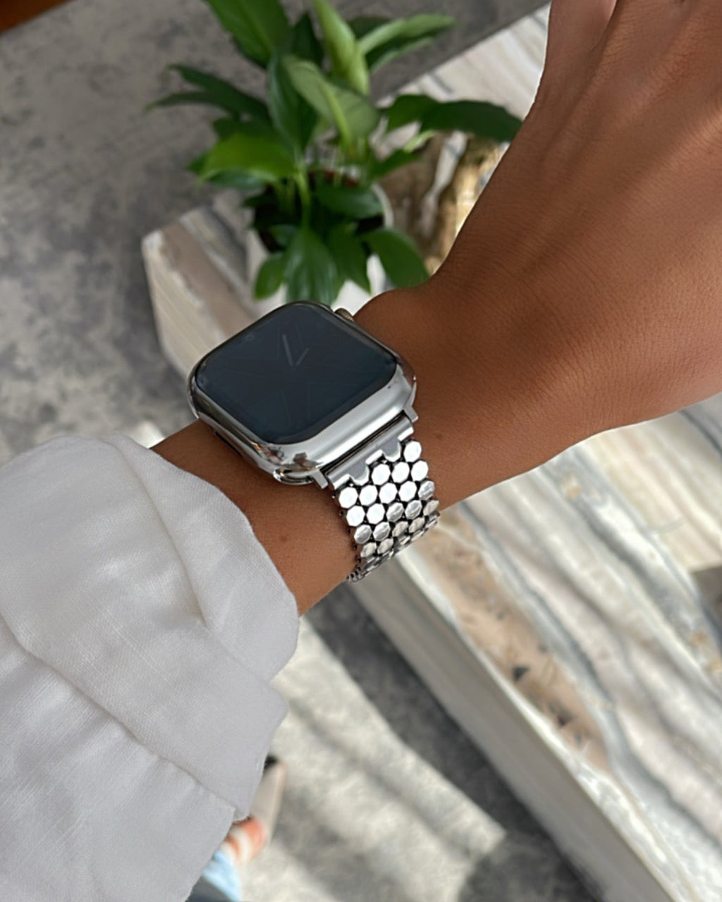 Person wearing a smartwatch with a metal band on a blurred background
