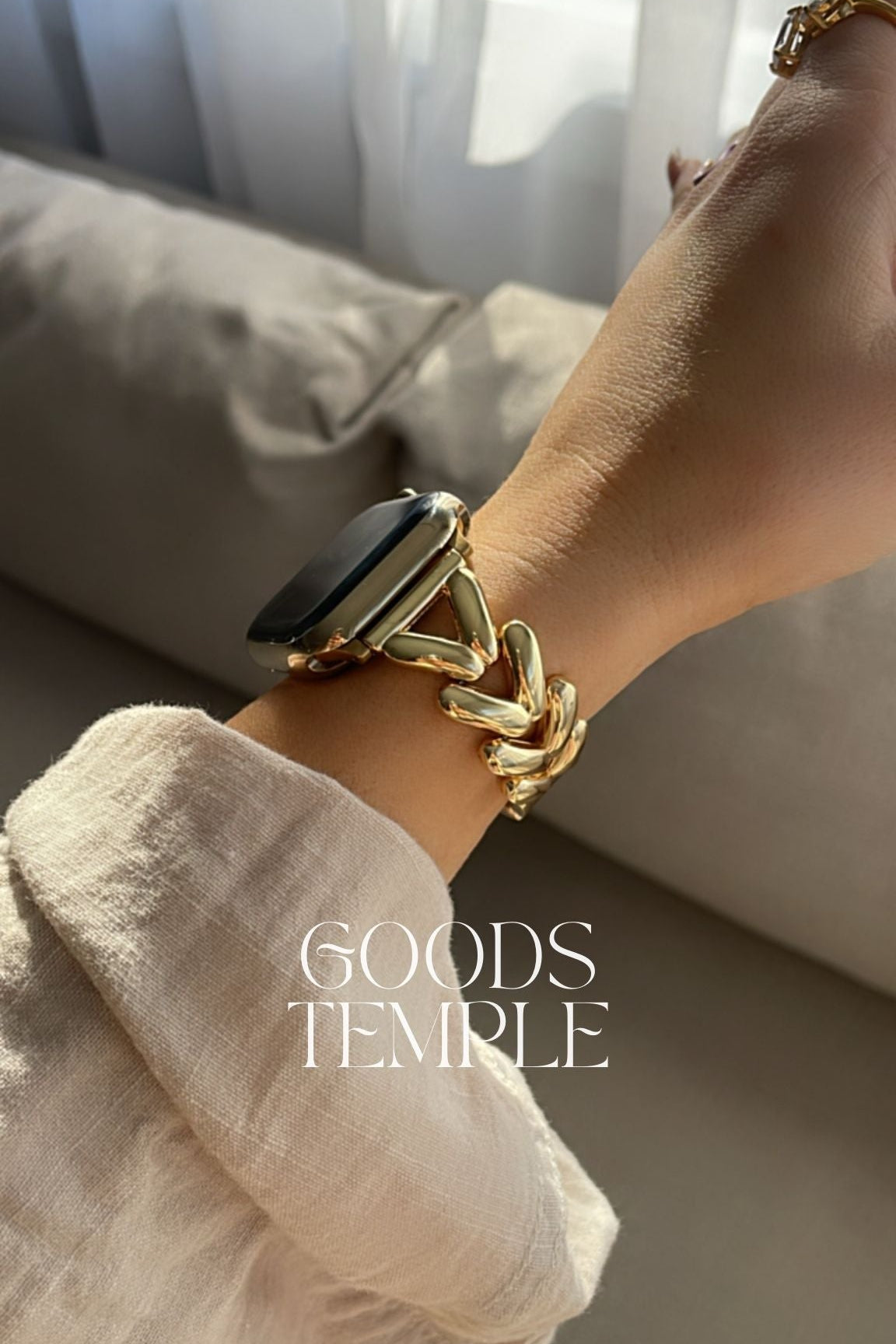 Gold bracelet on a wrist with a blurred background and 'GOODS TEMPLE' branding.