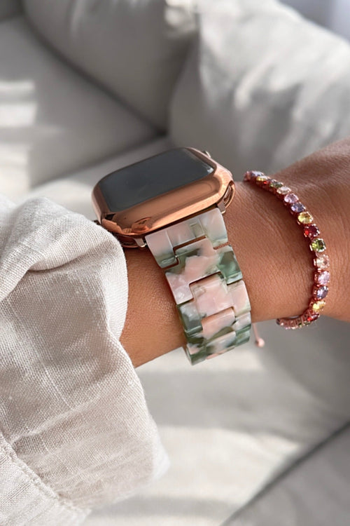 Smartwatch with a floral band on a wrist, wearing a white shirt and colorful bracelet.