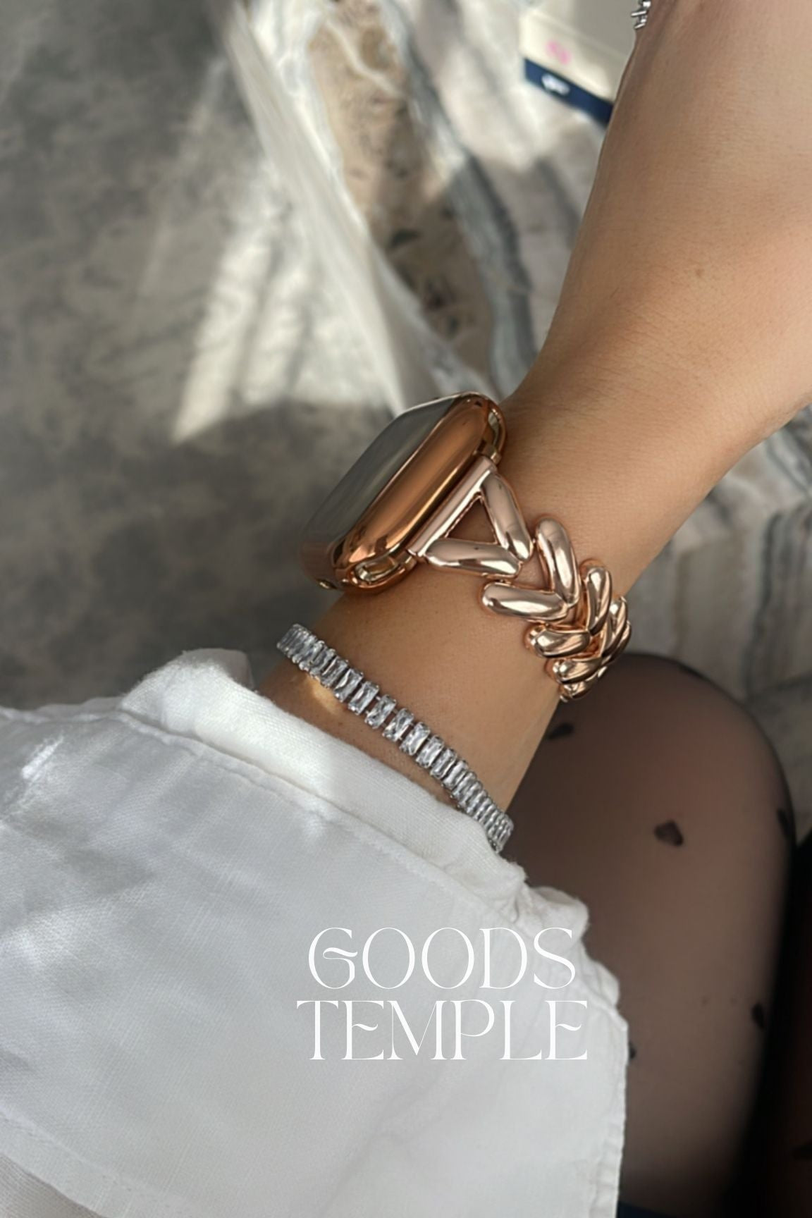 Close-up of a wrist wearing a gold bracelet with 'GOODS TEMPLE' branding.