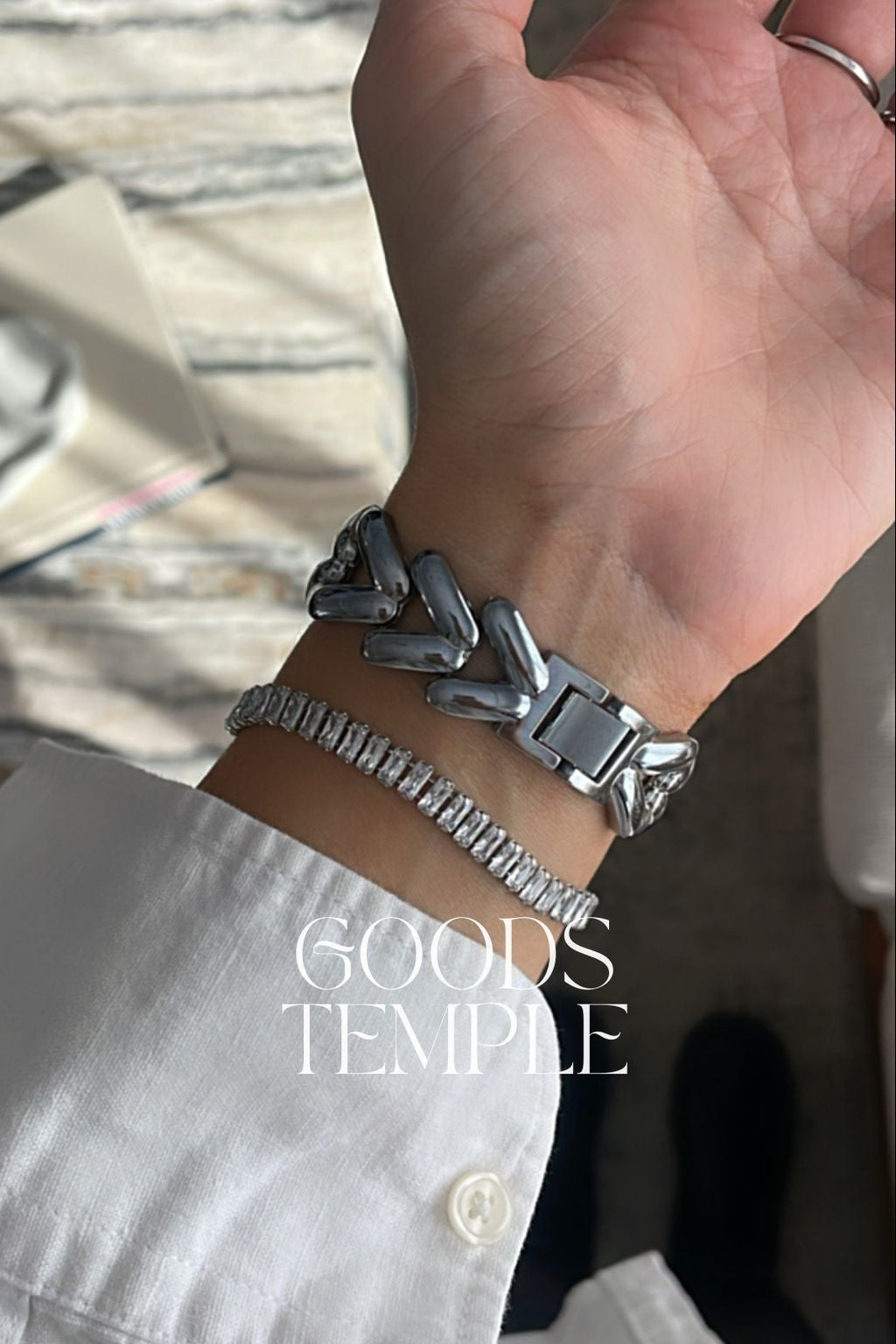 Hand wearing a silver bracelet with 'GOODS TEMPLE' branding.