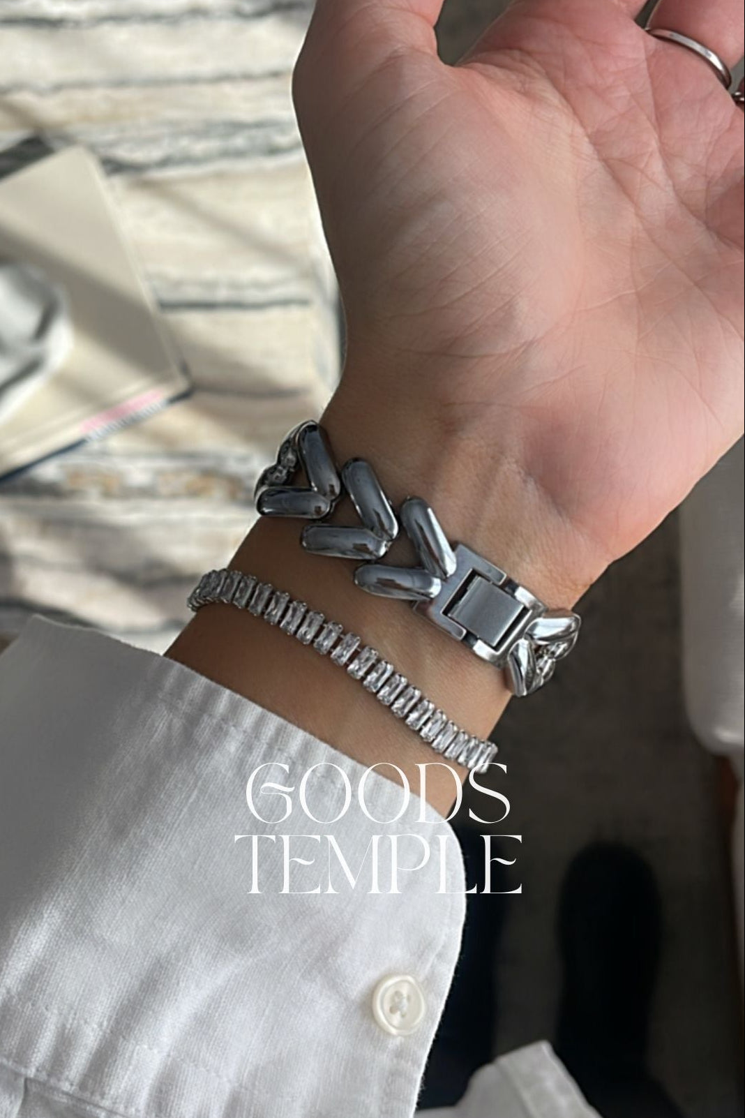 Hand wearing a silver bracelet with 'GOODS TEMPLE' branding.